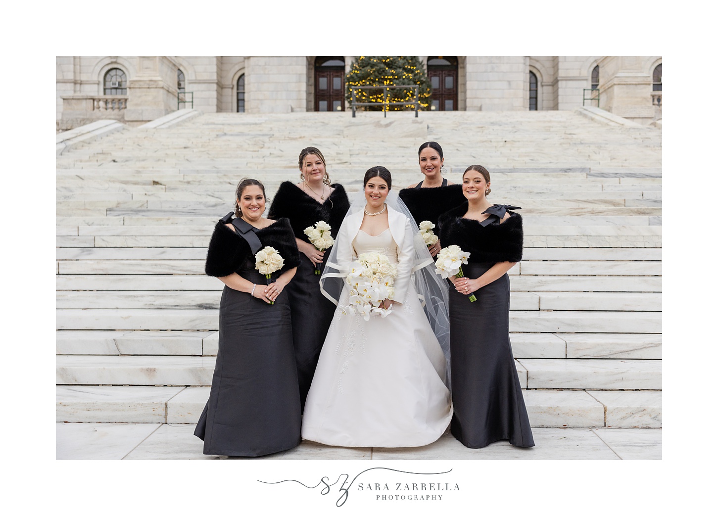 bride stands on steps with bridesmaids in black gowns at the RI State House