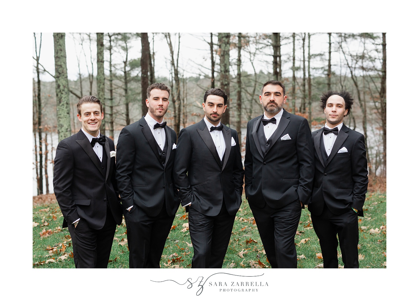 groom and groomsmen stand with hands in pockets of black suits 