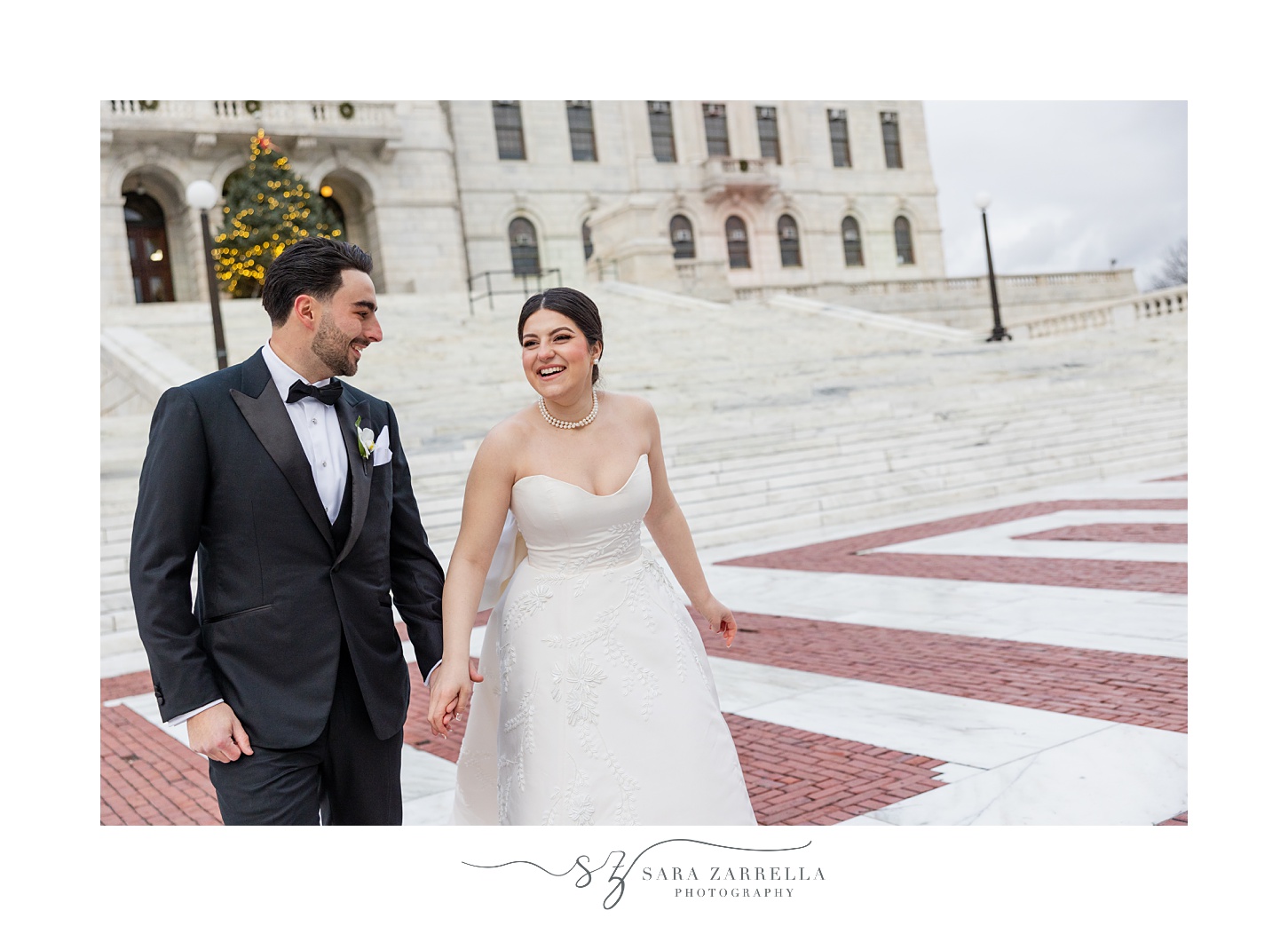 bride smiles at groom walking across brick patio outside the RI State House