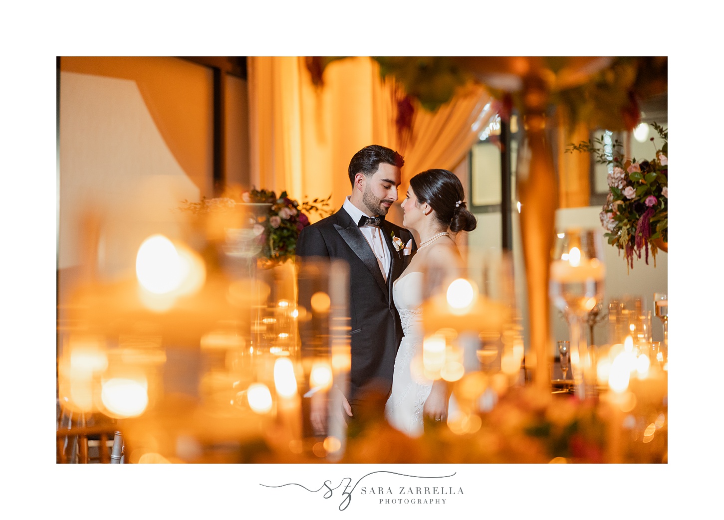 newlyweds hug behind candles in foreground 