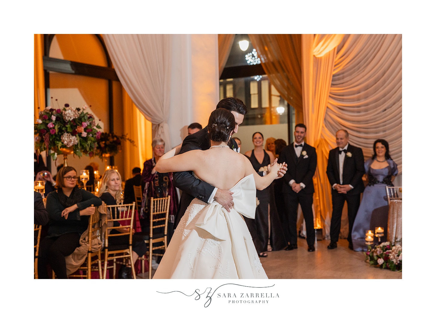 groom dances with bride holding the bow on the back of her gown at the ballroom at the Providence G