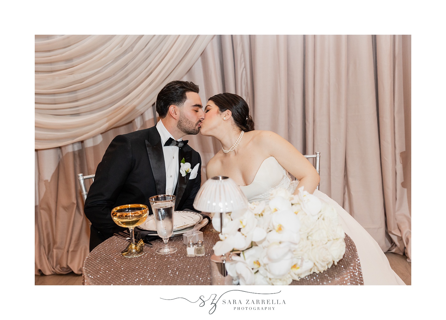 newlyweds kiss at sweetheart table during reception at the ballroom at the Providence G