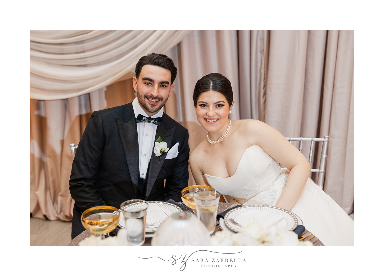 bride and groom smile sitting together at sweetheart table 