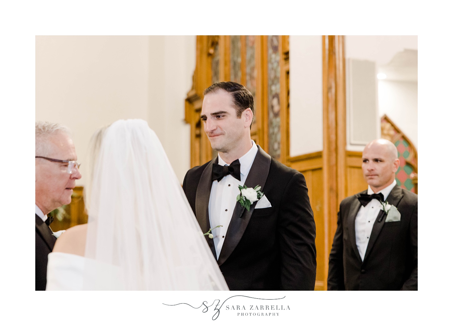 groom smiles at bride inside Saint Francis of Assisi Parish