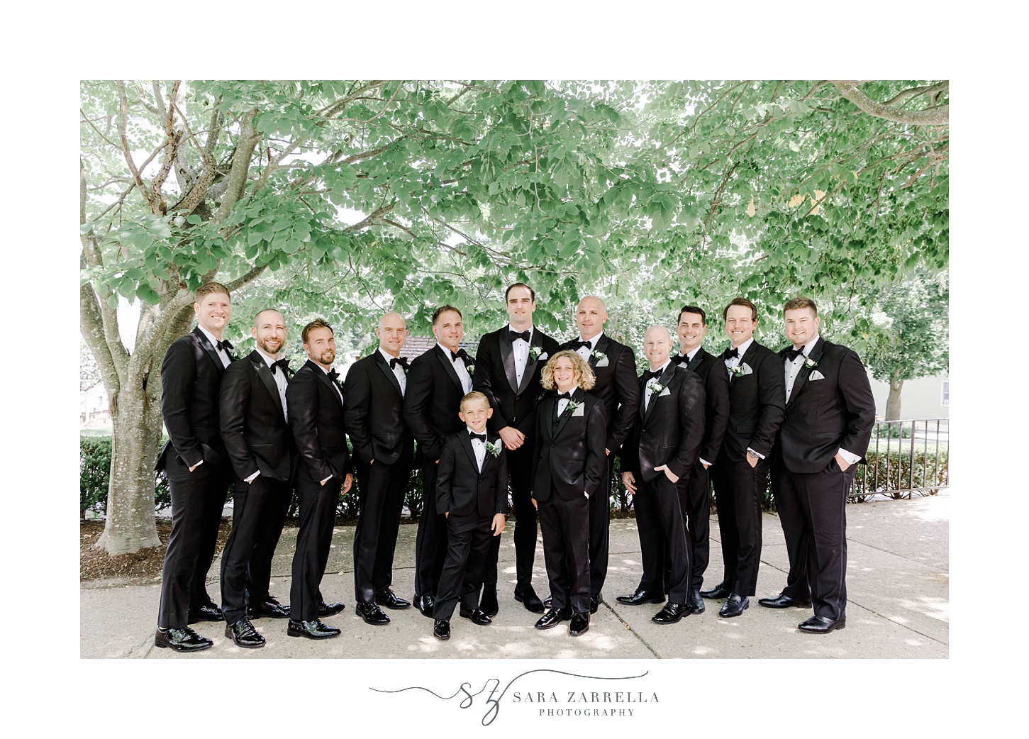groom stands with groomsmen in black suits at the Dunes Club