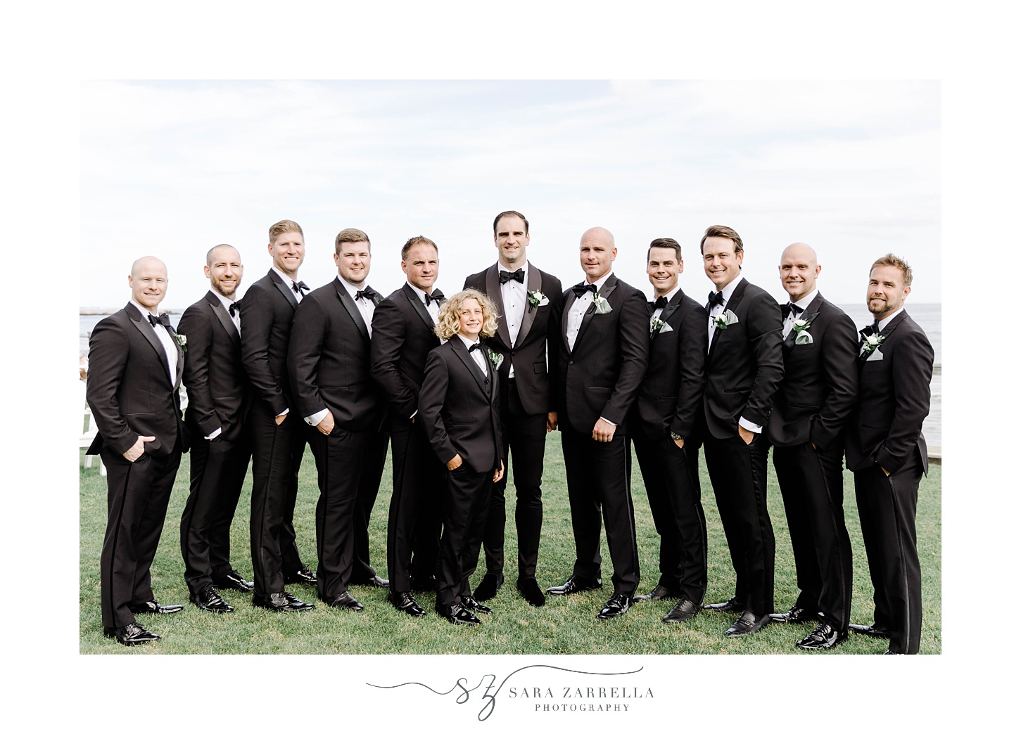 groom and groomsmen pose together on lawn outside the Dunes Club