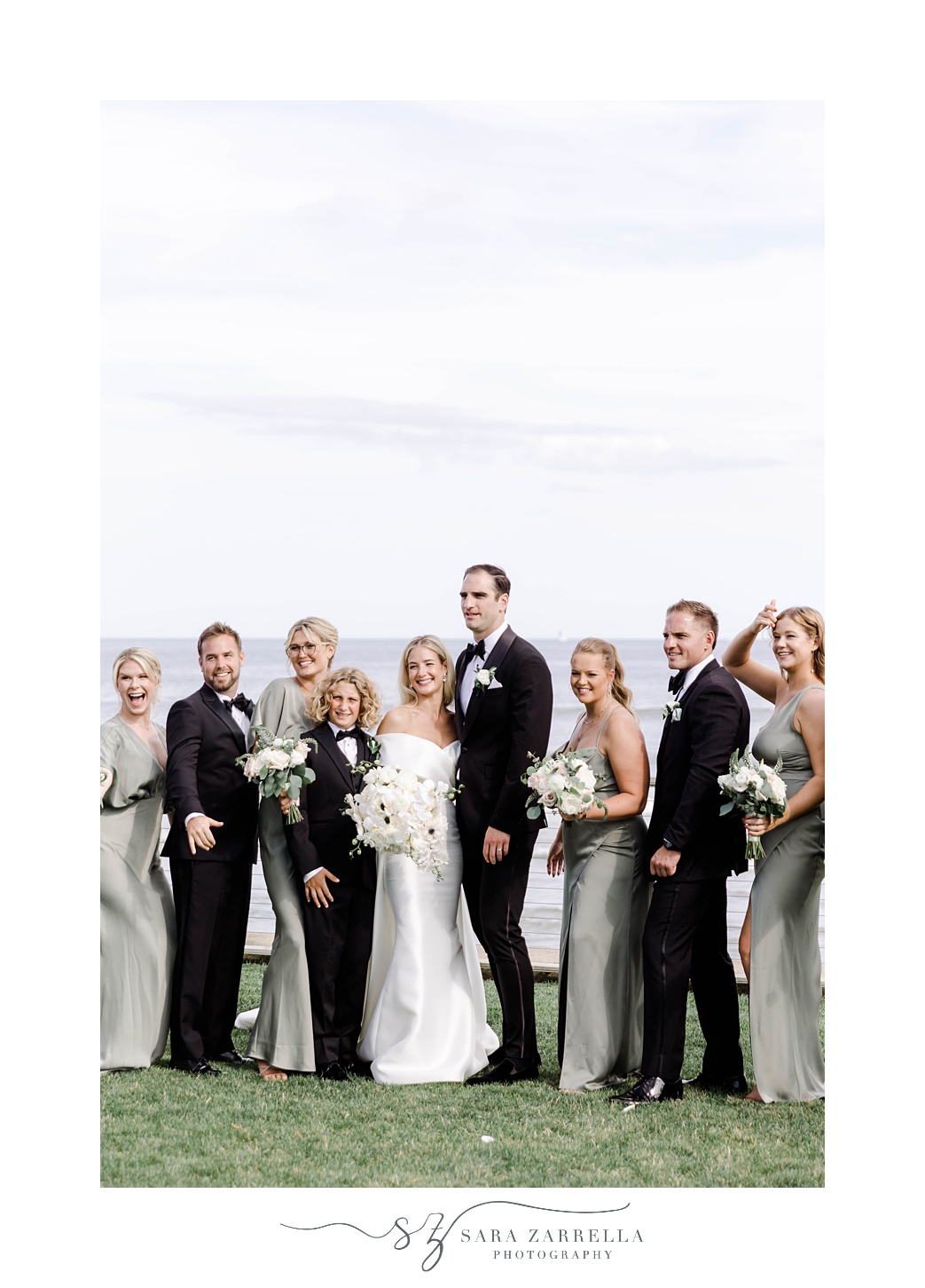 bride and groom laugh with wedding party in black suit and green dresses at the Dunes Club