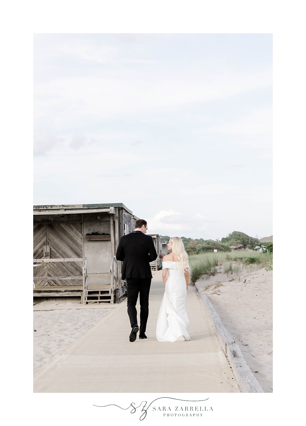 bride and groom walk on the beach near Narragansett Bay