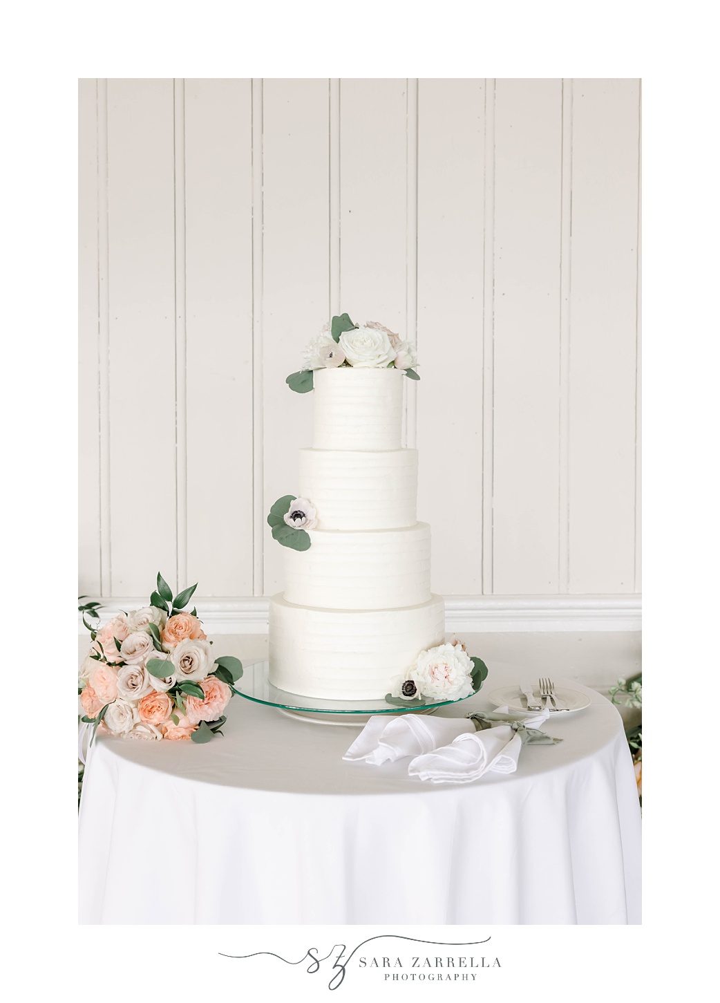 tiered wedding cake with white icing and flowers at the Dunes Club