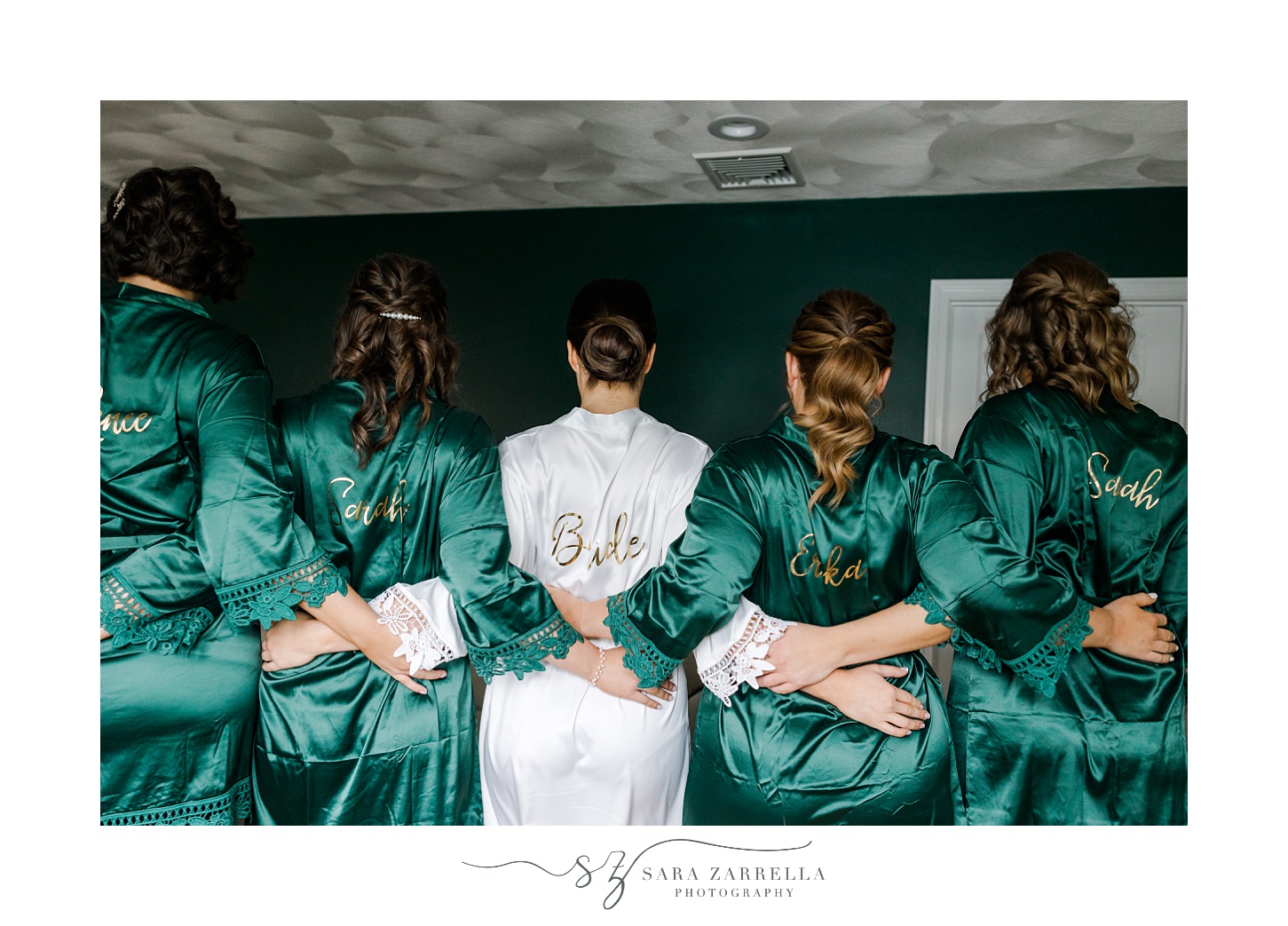 bride hugs bridesmaids in matching emerald robes