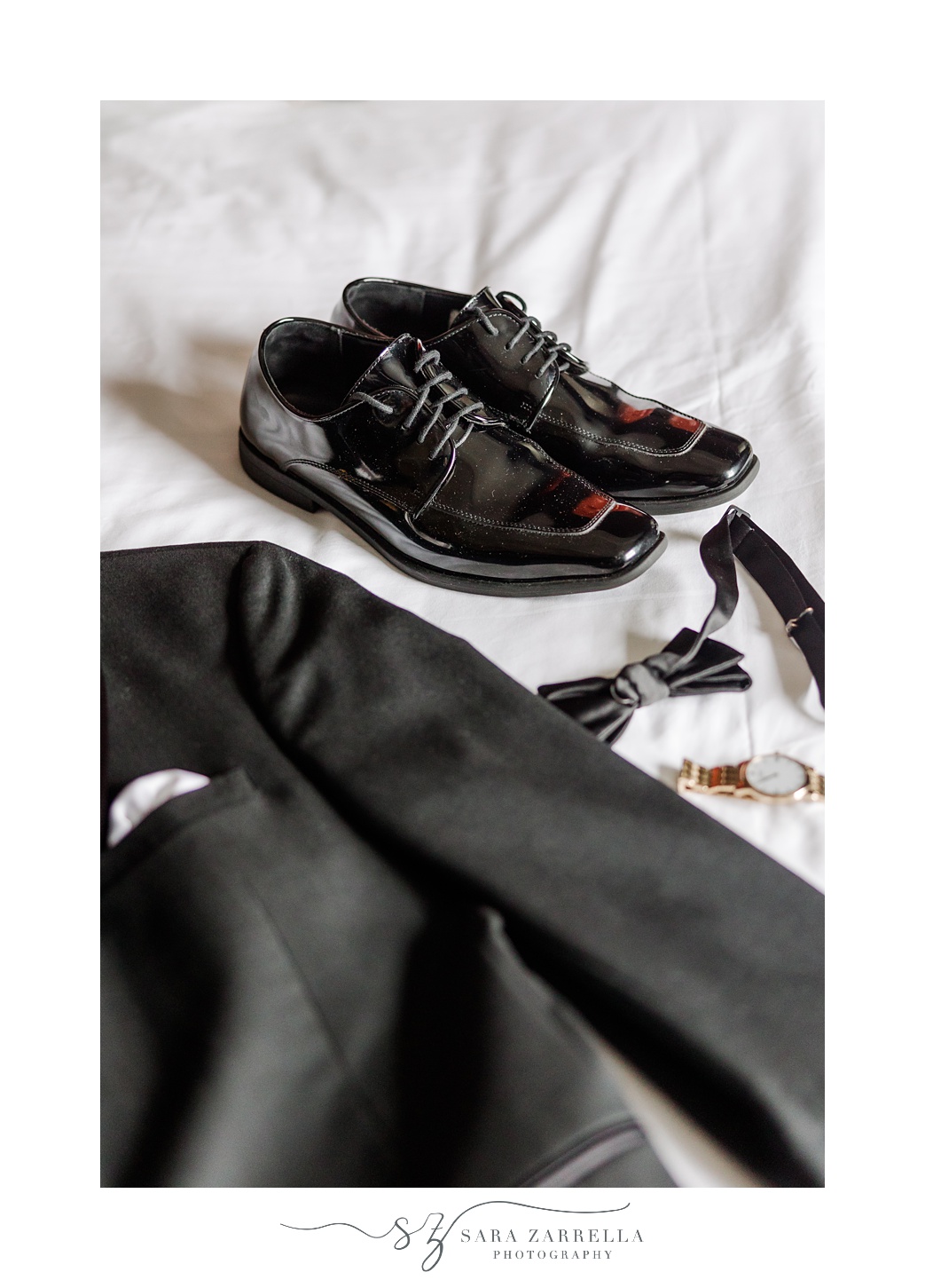 groom's black shoes and jacket lay on bed during prep for New Year's Eve wedding