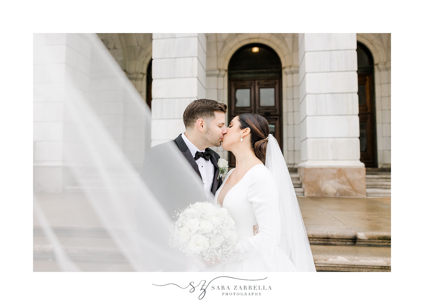 newlyweds kiss with veil floating in front of them outside the Rhode Island State House in Providence RI