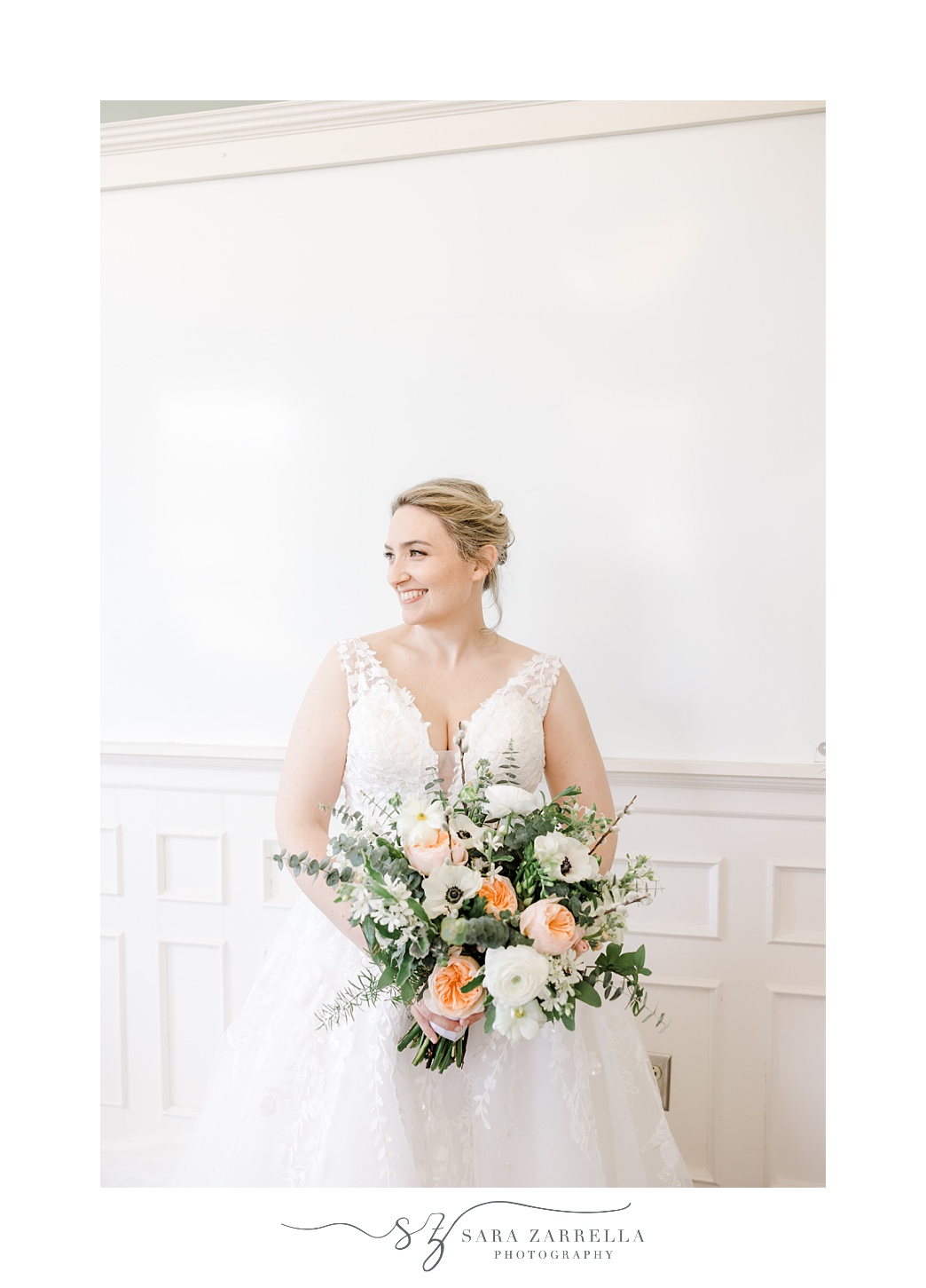 bride smiles over shoulder holding wedding bouquet in East Greenwich Town Hall