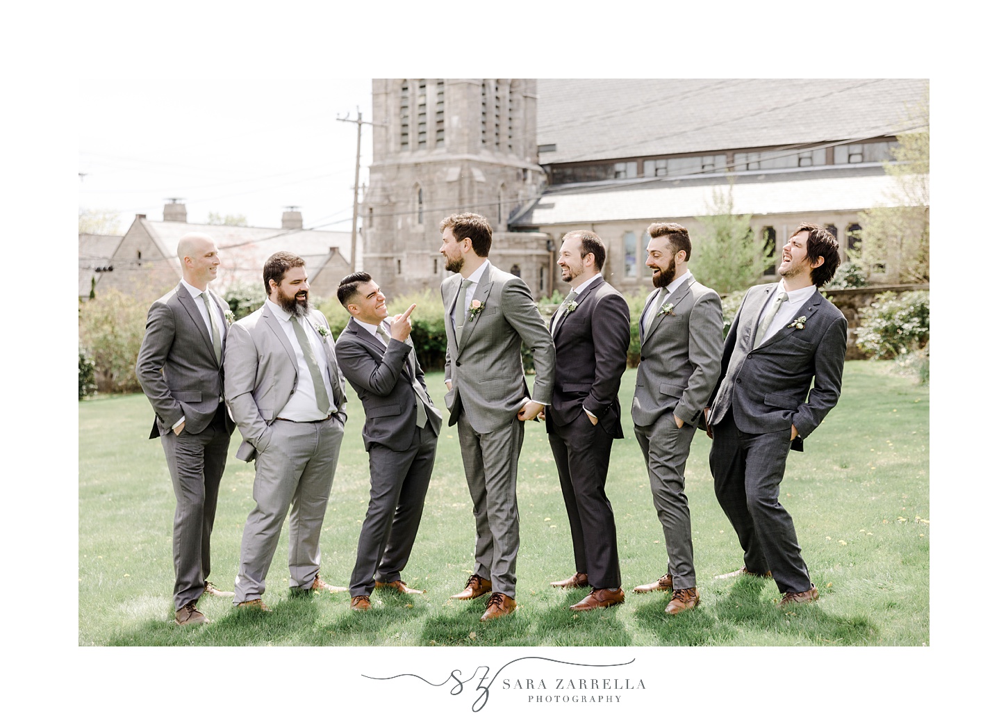 groom laughs with groomsmen in front of church in East Greenwich