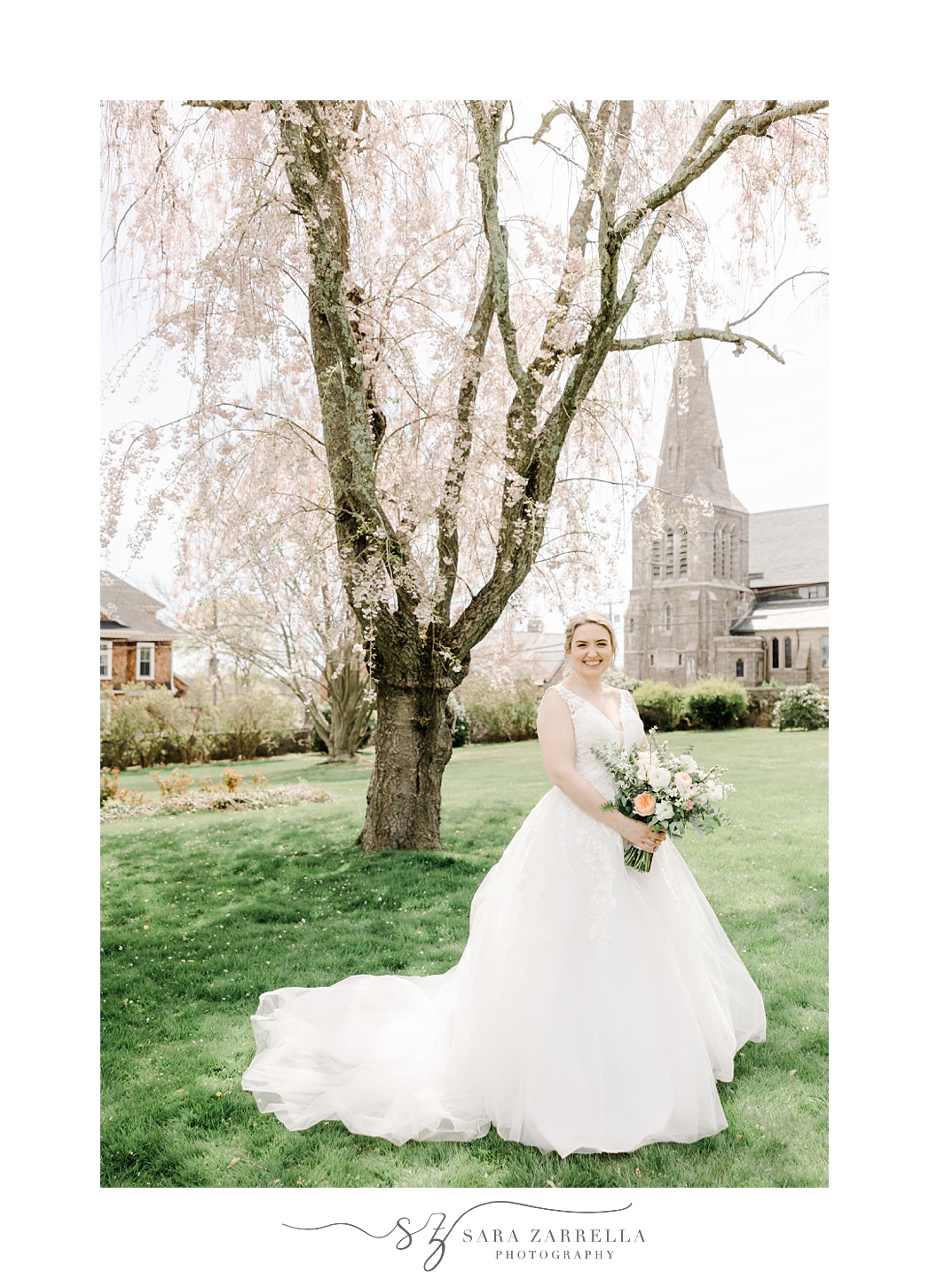 bride holds spring bouquet standing on lawn in East Greenwich RI in front of church 