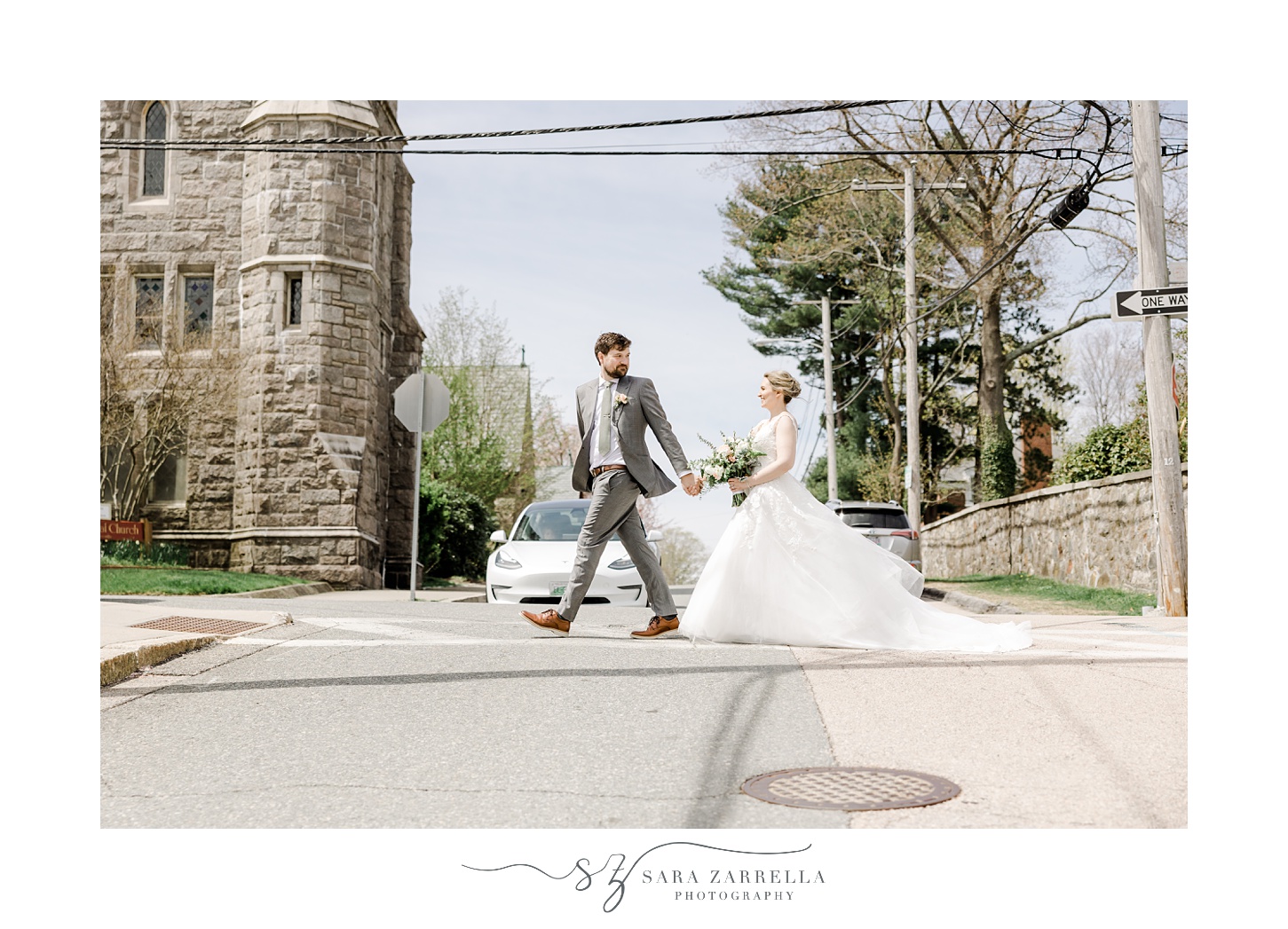 bride and groom hold hands crossing the street in East Greenwich RI