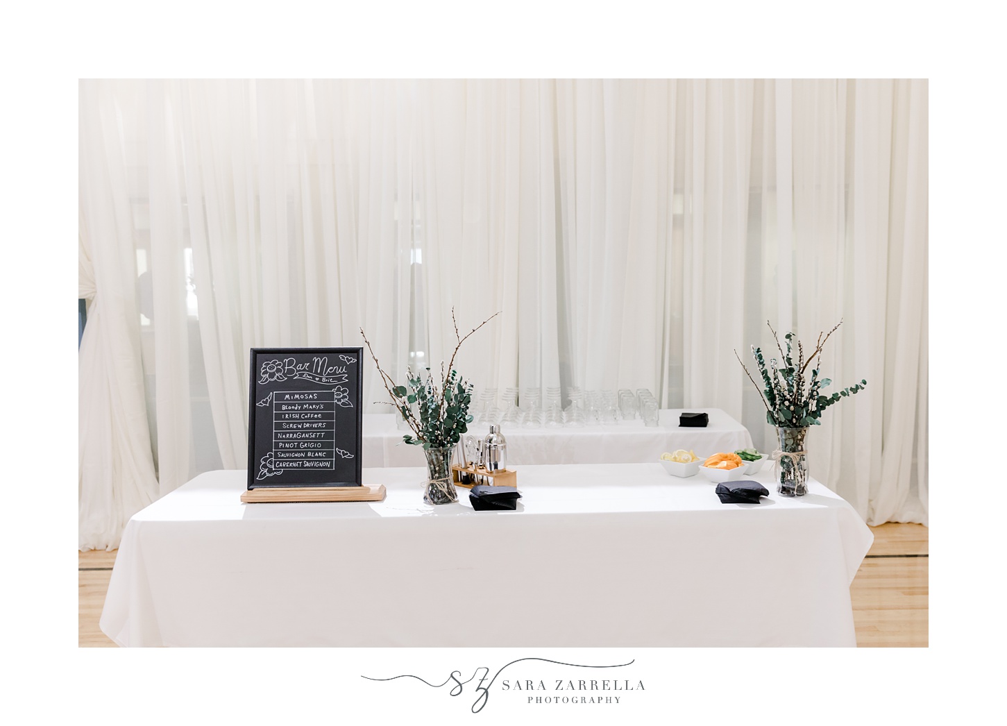gift table with candle and greenery in flower vases 