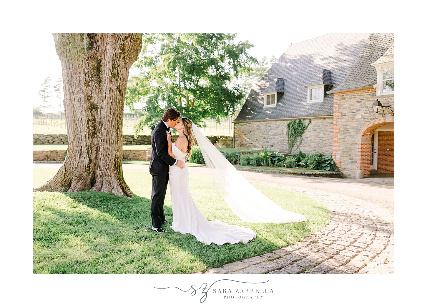 newlyweds kiss under oak tree at Shepard's Run with veil floating behind them