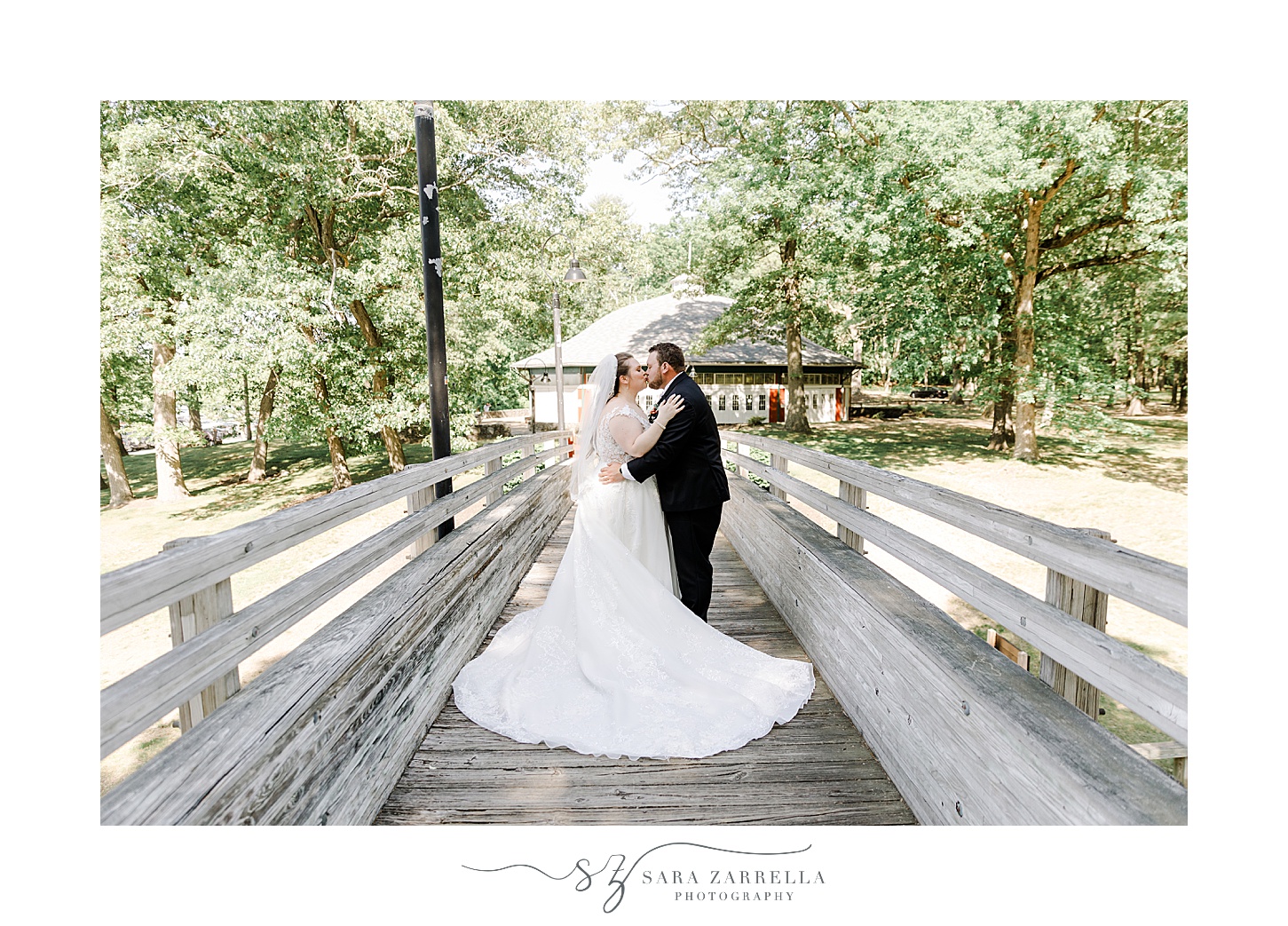 newlyweds stand on wooden bridge with wedding gown train around them