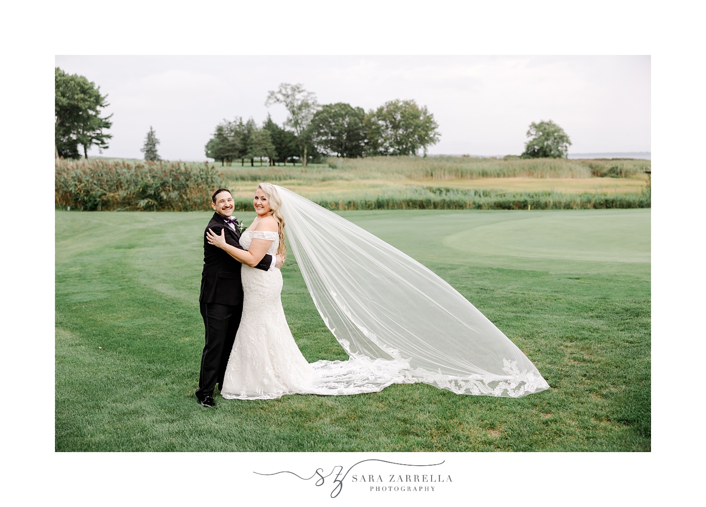 bride and groom hug with bride's veil floating behind them at Quidnessett Country Club