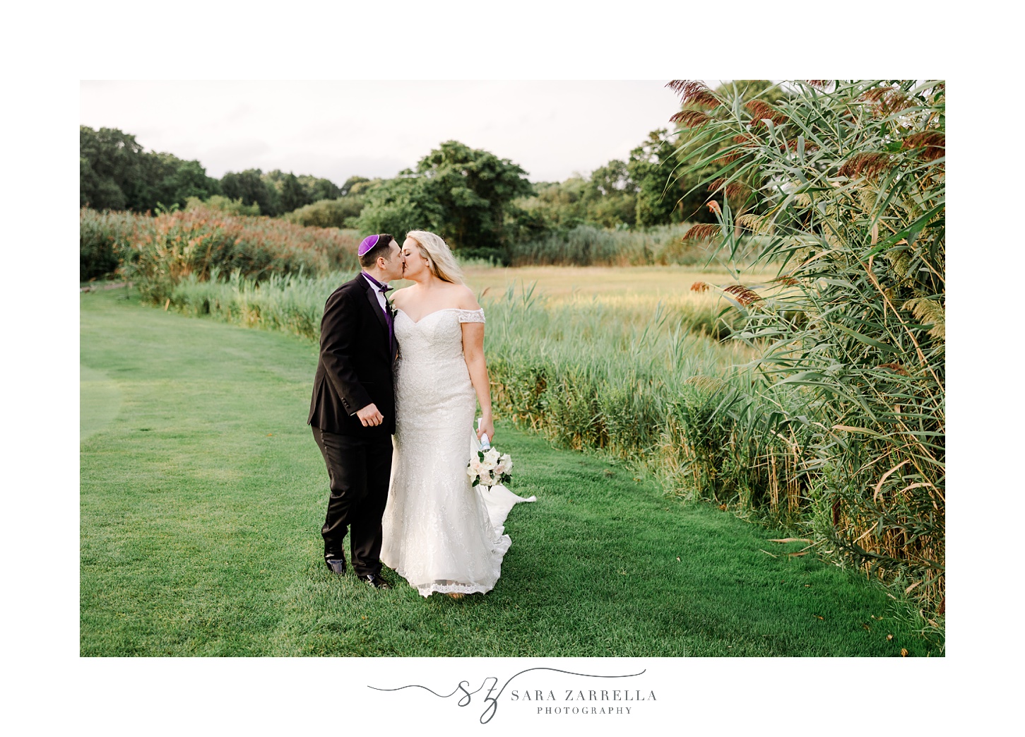 newlyweds kiss near tall grass at Quidnessett Country Club