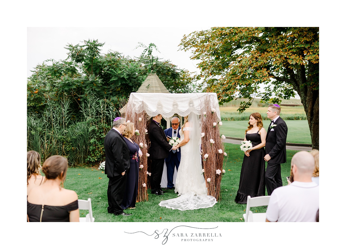 families stand with bride and groom during Jewish wedding ceremony on the lawn at Quidnessett Country Club