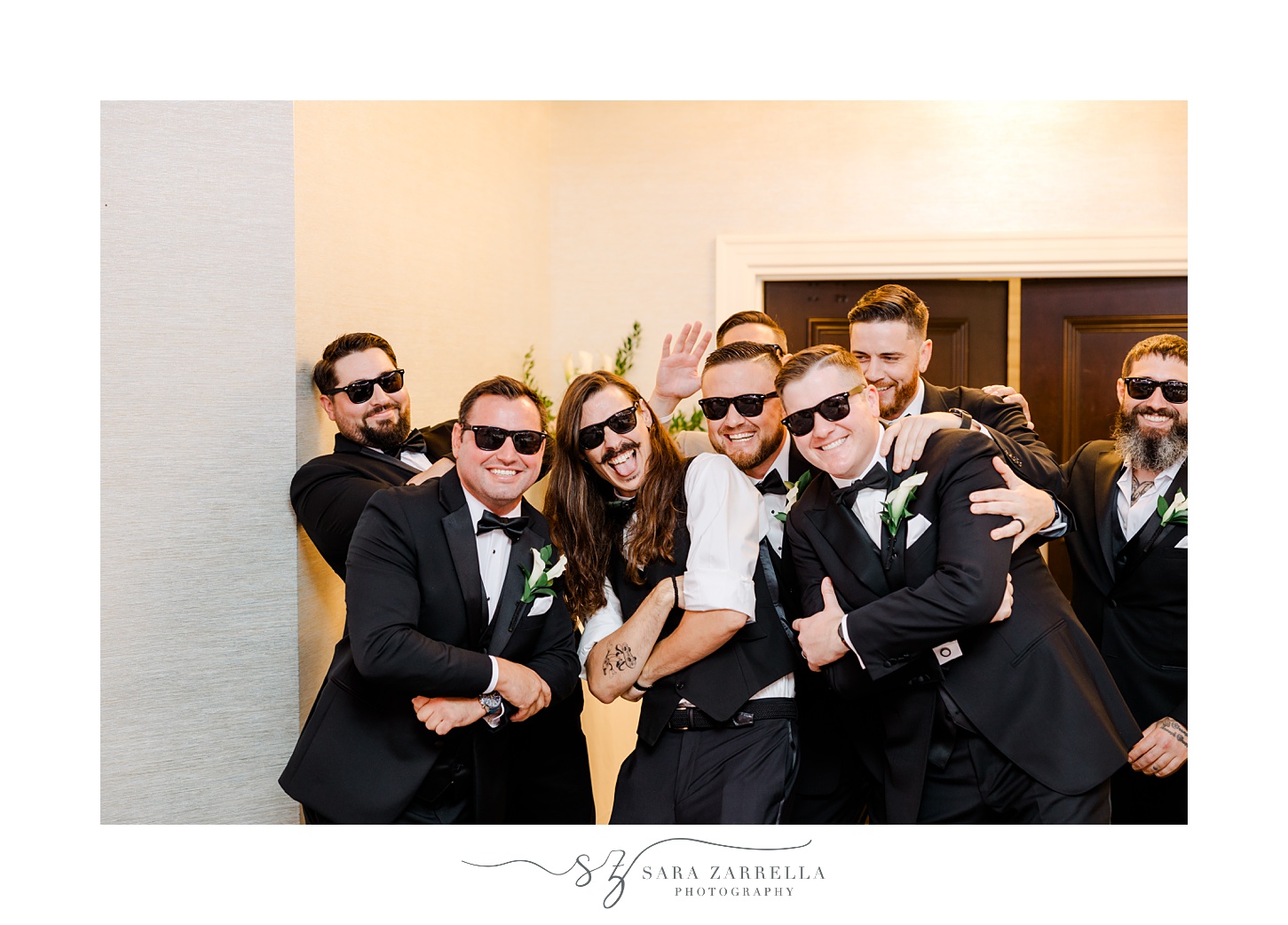 groom and groomsmen laugh wearing sunglasses in ballroom at Quidnessett Country Club