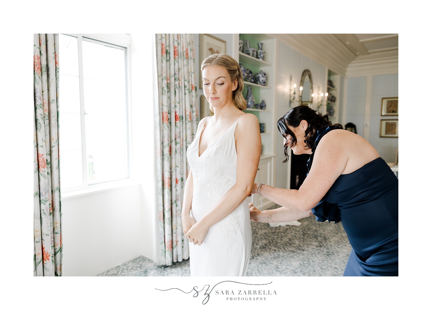 woman in navy blue dress helps bride with wedding gown