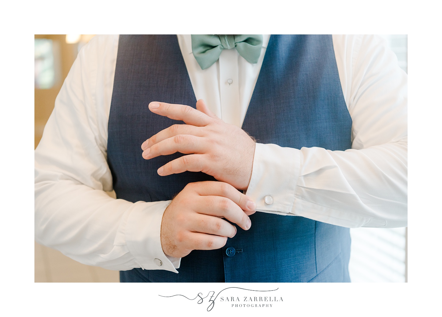 groom adjusts cufflinks before wedding day in Rhode Island