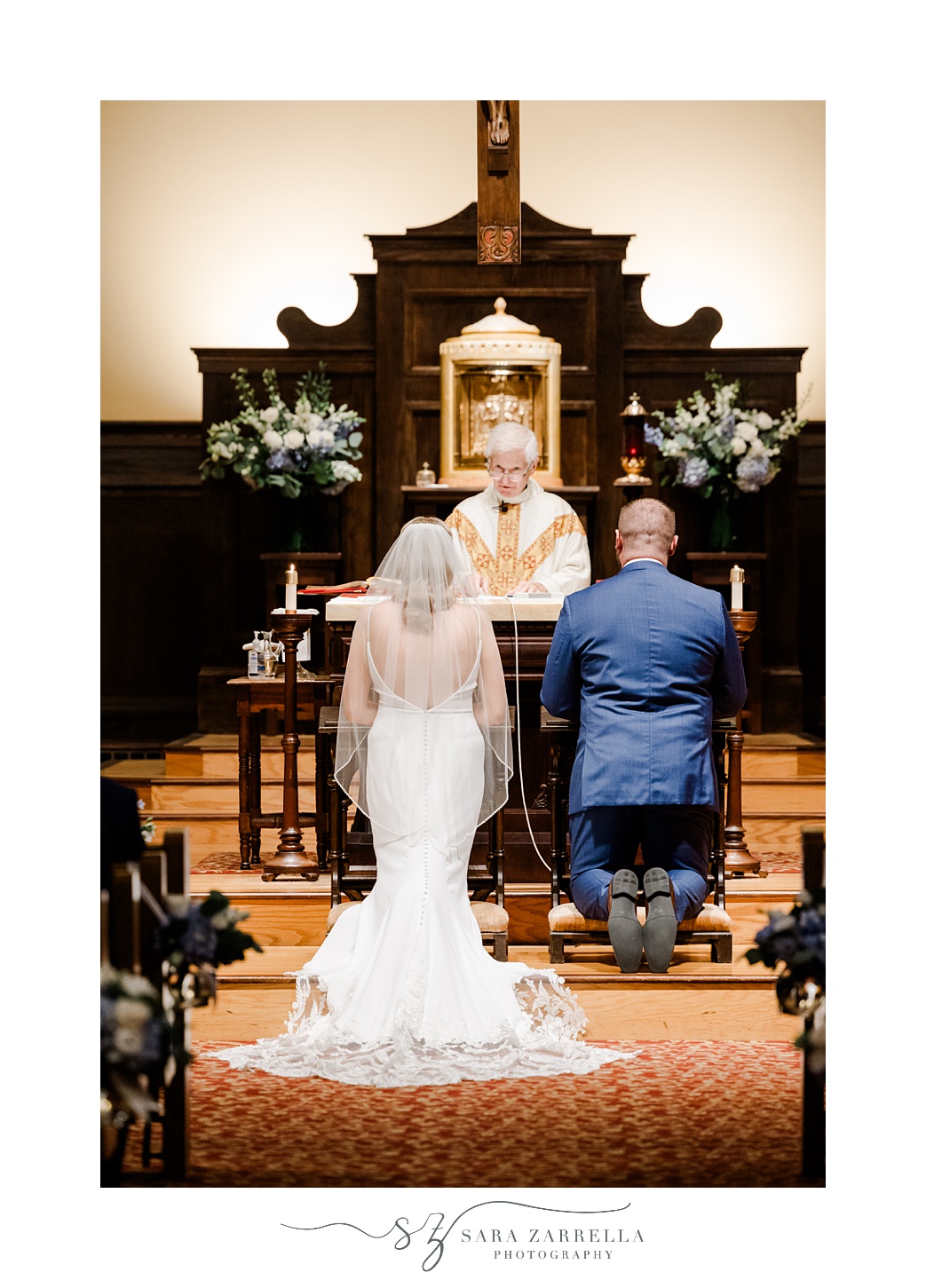 bride and groom kneel at alter during traditional church wedding at St. Thomas More Church