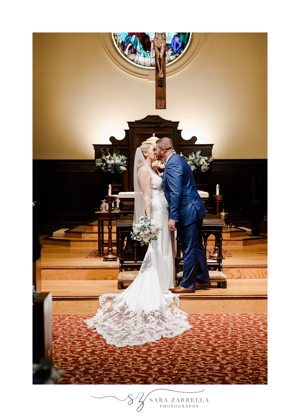 newlyweds kiss at alter during traditional church wedding at St. Thomas More Church