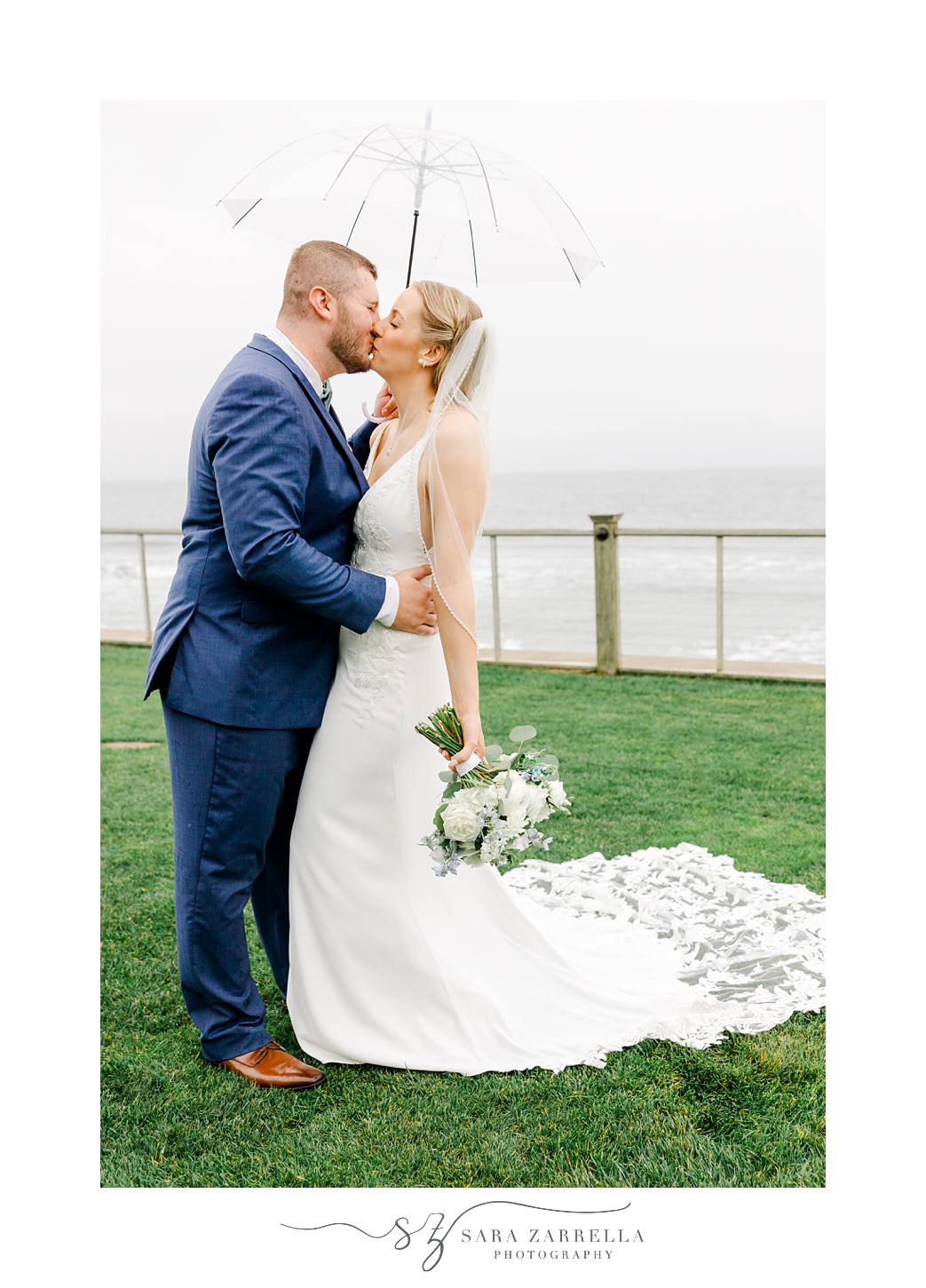 bride and groom kiss under clear umbrella on rainy wedding day at the Dunes Club