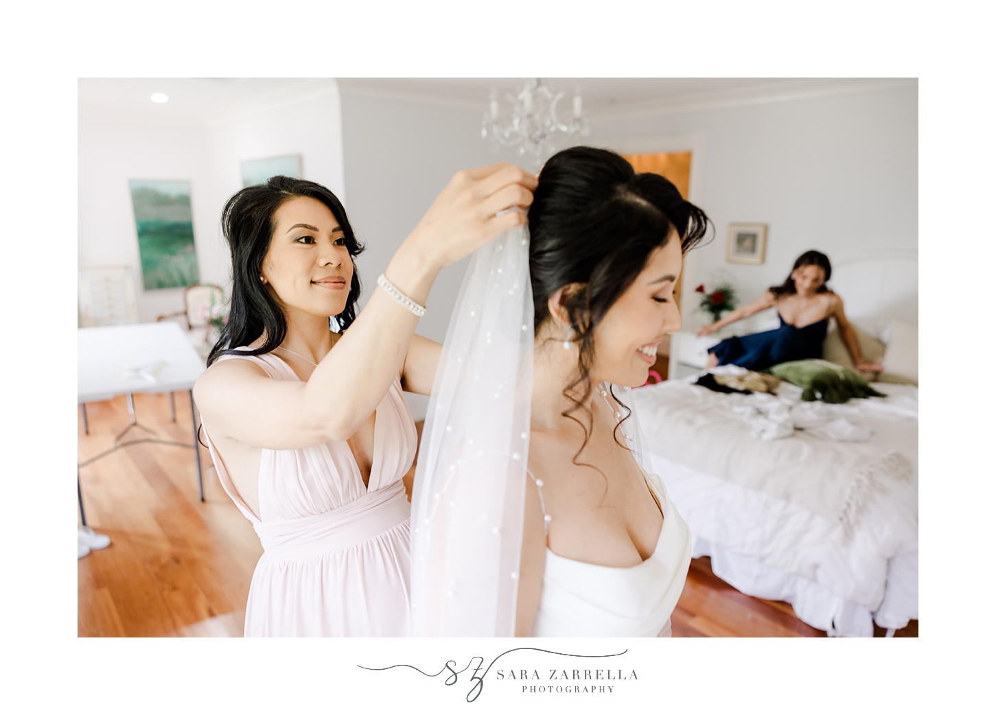 woman smiles as she places bride's veil in hair during prep in Cranston RI home