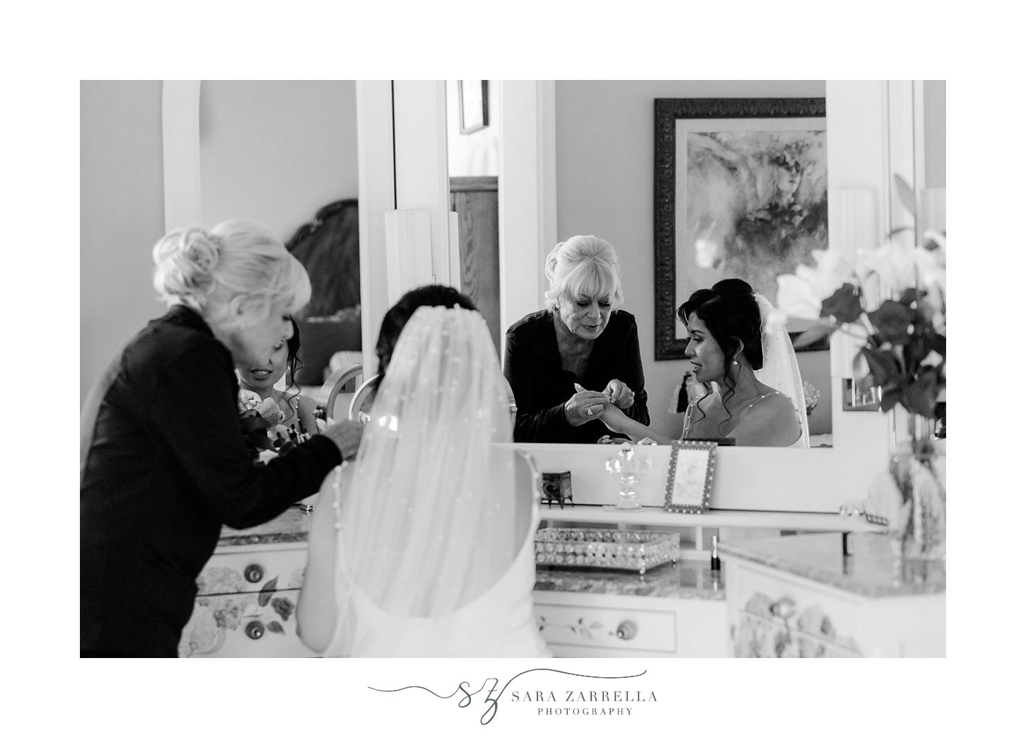older woman helps bride with bracelets at table in bedroom