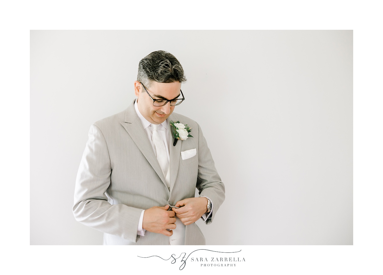 groom pulls suit jacket closed while preparing for wedding in Cranston RI