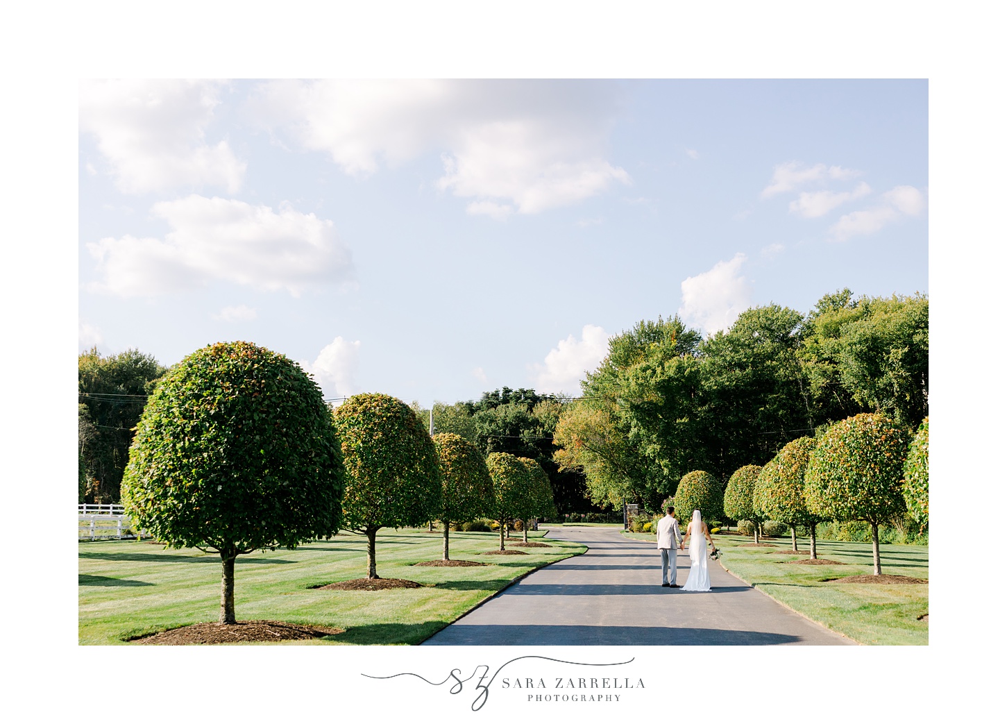 bride and groom hold hands walking down driveway of Rhode Island home