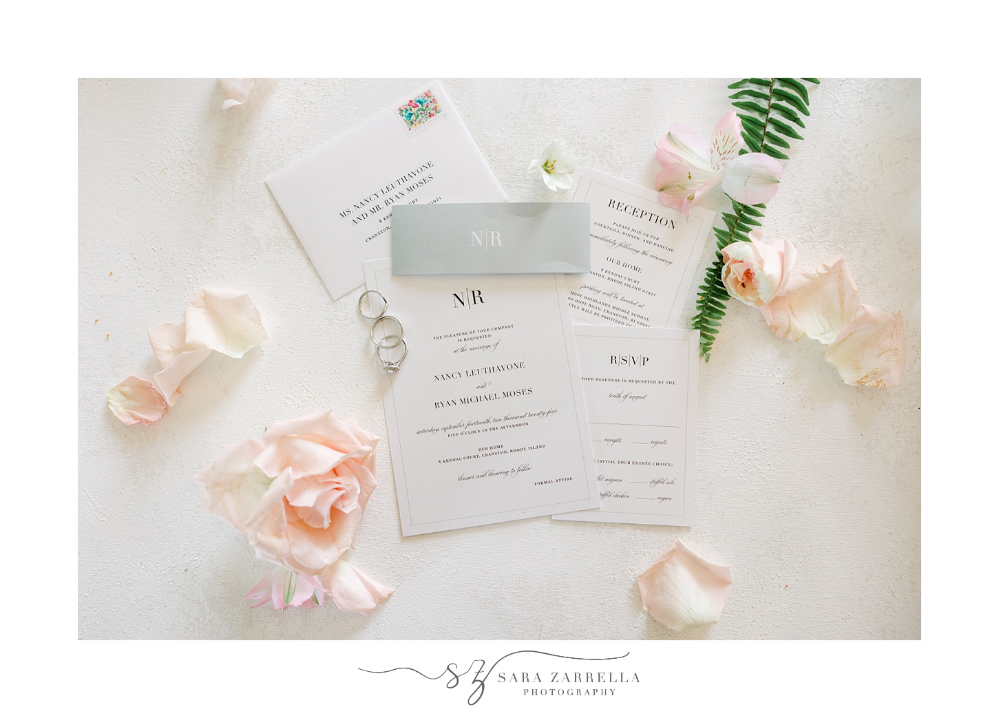 invitation suite with pink rose petals around it on marbled surface