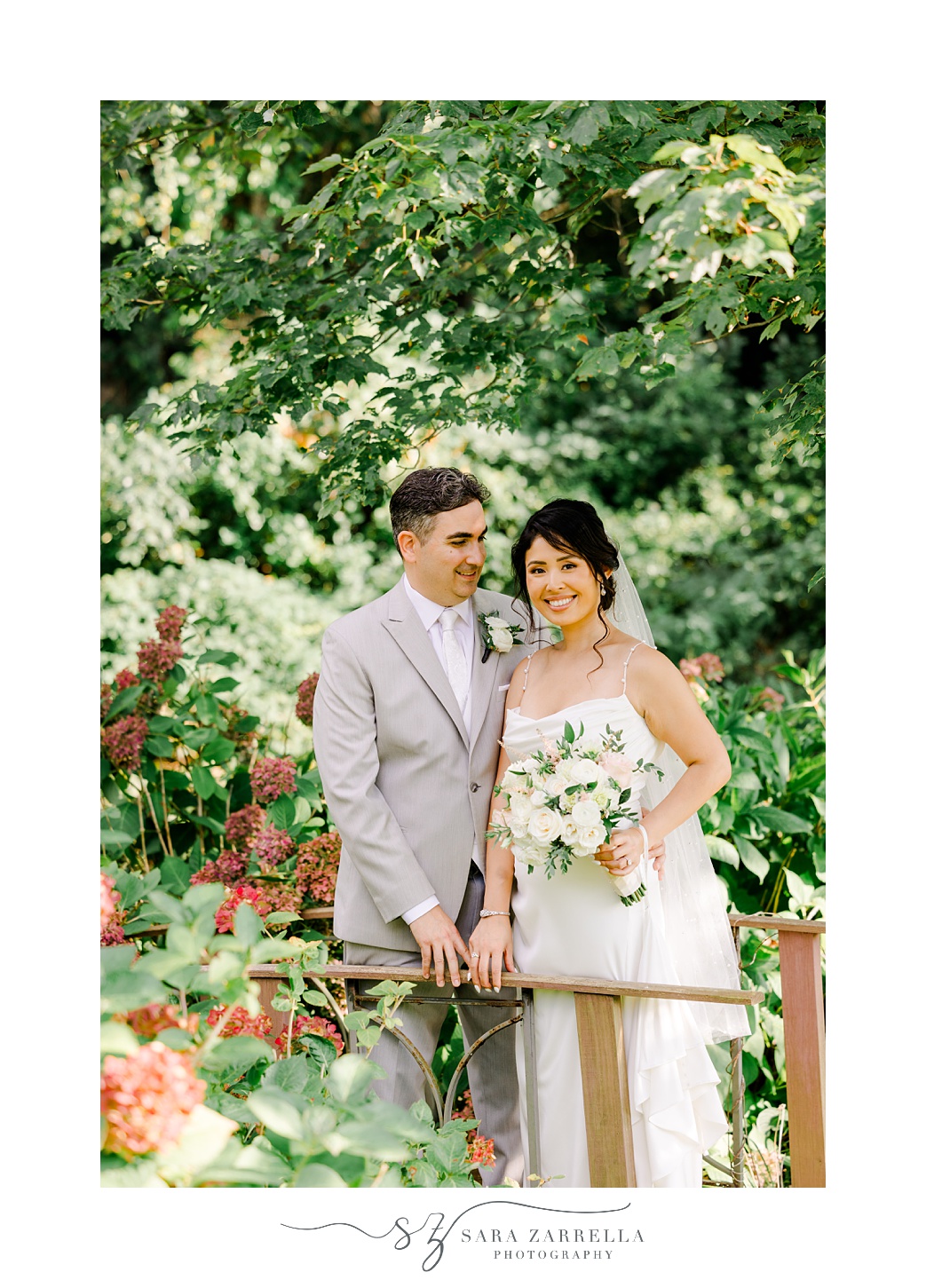 newlywed stand together on wooden bridge in backyard garden