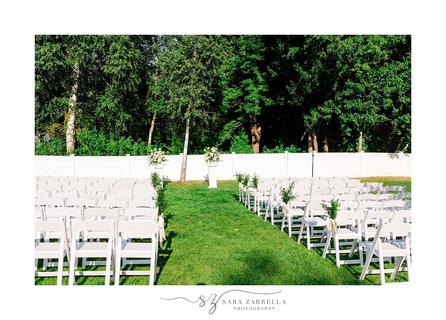view of ceremony site on lawn with white chairs and flowers for backyard wedding ceremony in Cranston RI