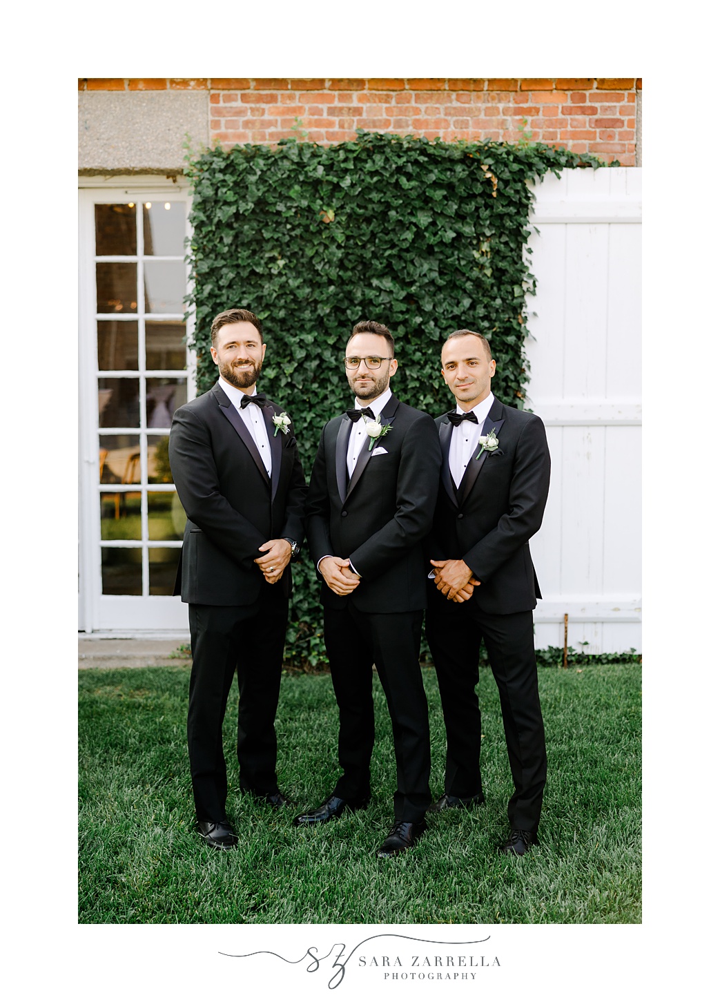 groom stands with groomsmen in front of ivy covered wall at Shepard's Run
