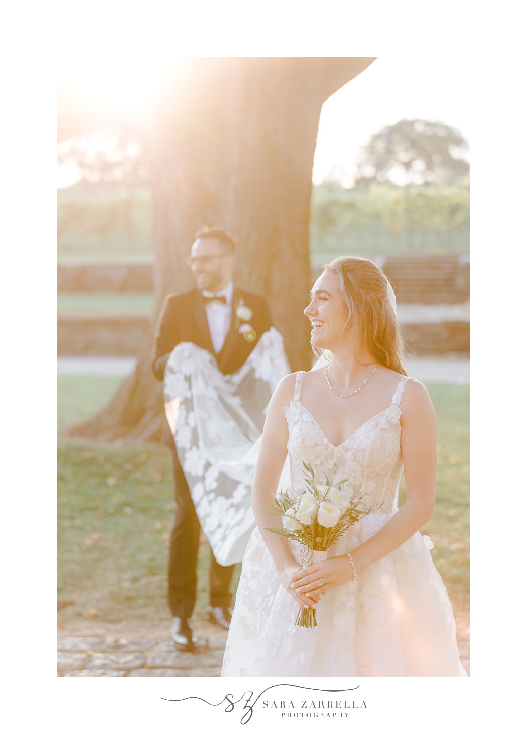 hazy photo of groom holding bride's veil out during portraits