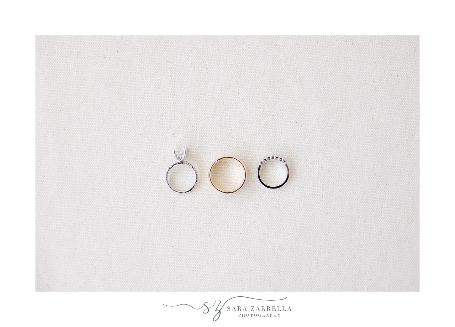 three wedding rings rest on ivory background for RI wedding