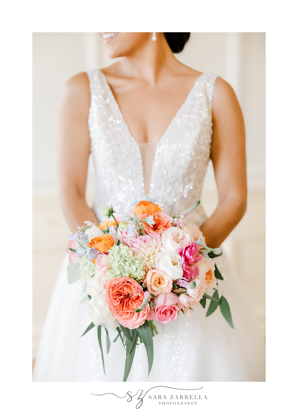 bride holds bouquet of bright orange, coral, and pink flowers