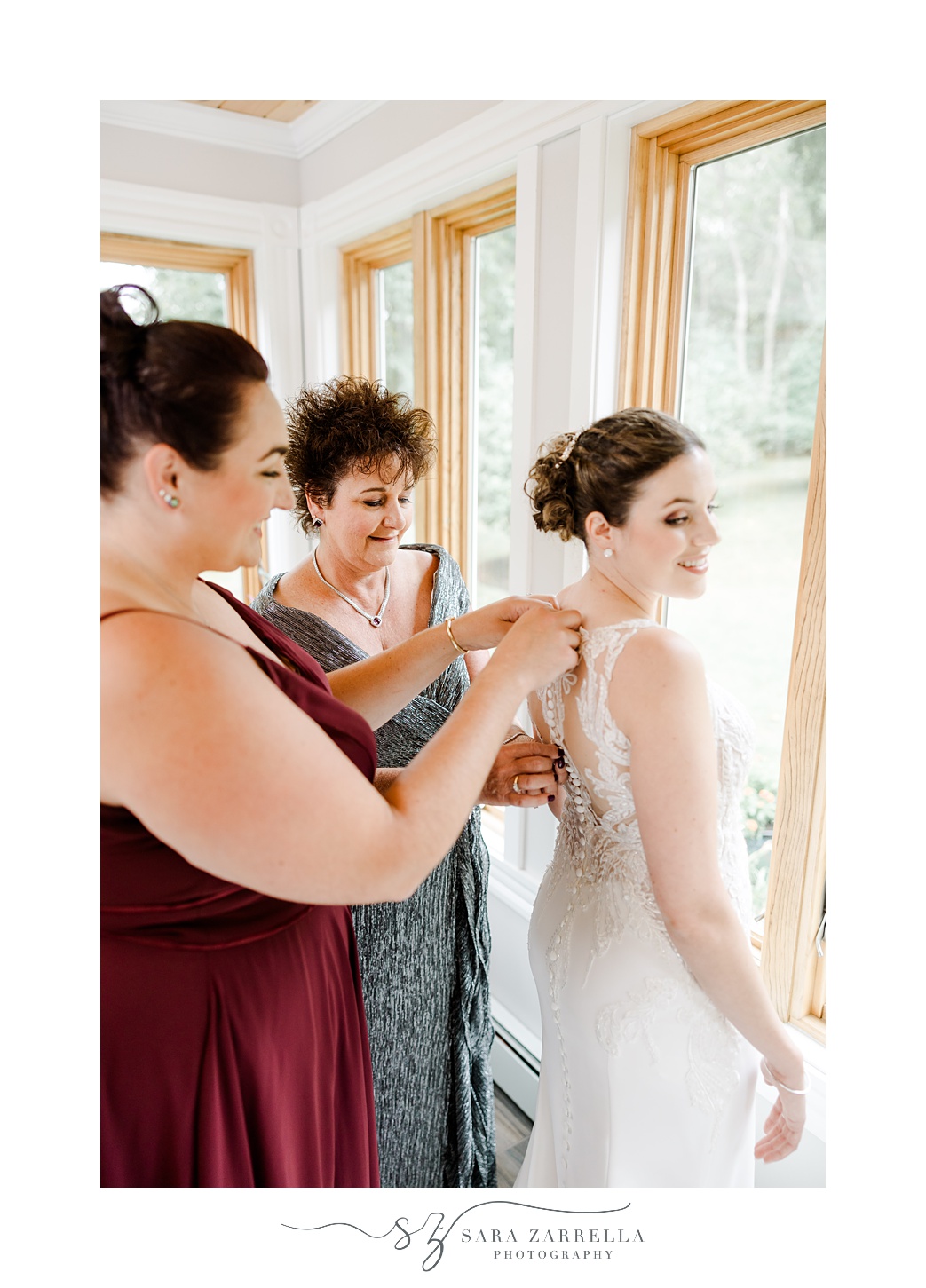 bridesmaid helps bride with gown and necklace during prep at Providence RI home