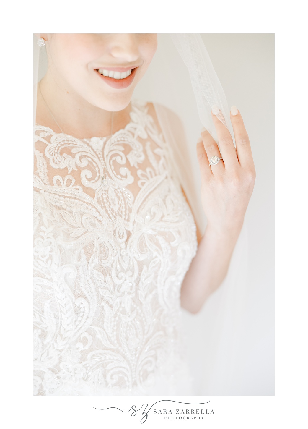 bride pulls veil around shoulders showing off engagement ring