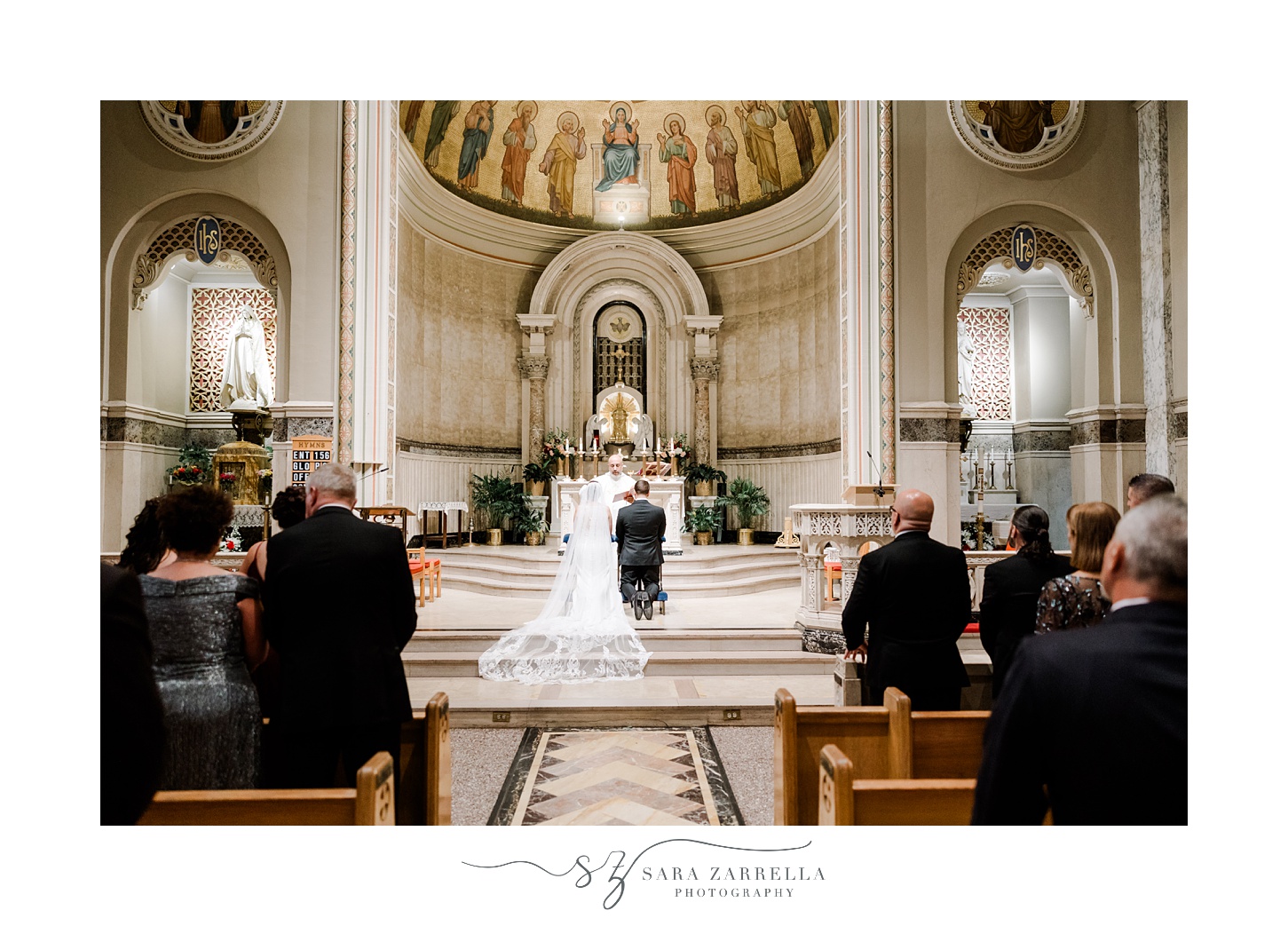 bride and groom kneel during ceremony inside the Holy Ghost Church