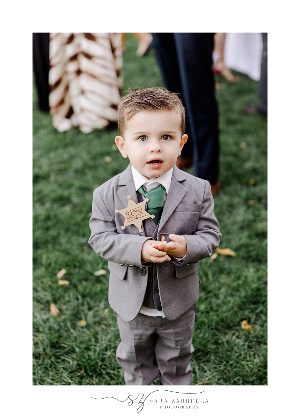 ring bearer smiles with "ring security" sheriff's badge on his jacket