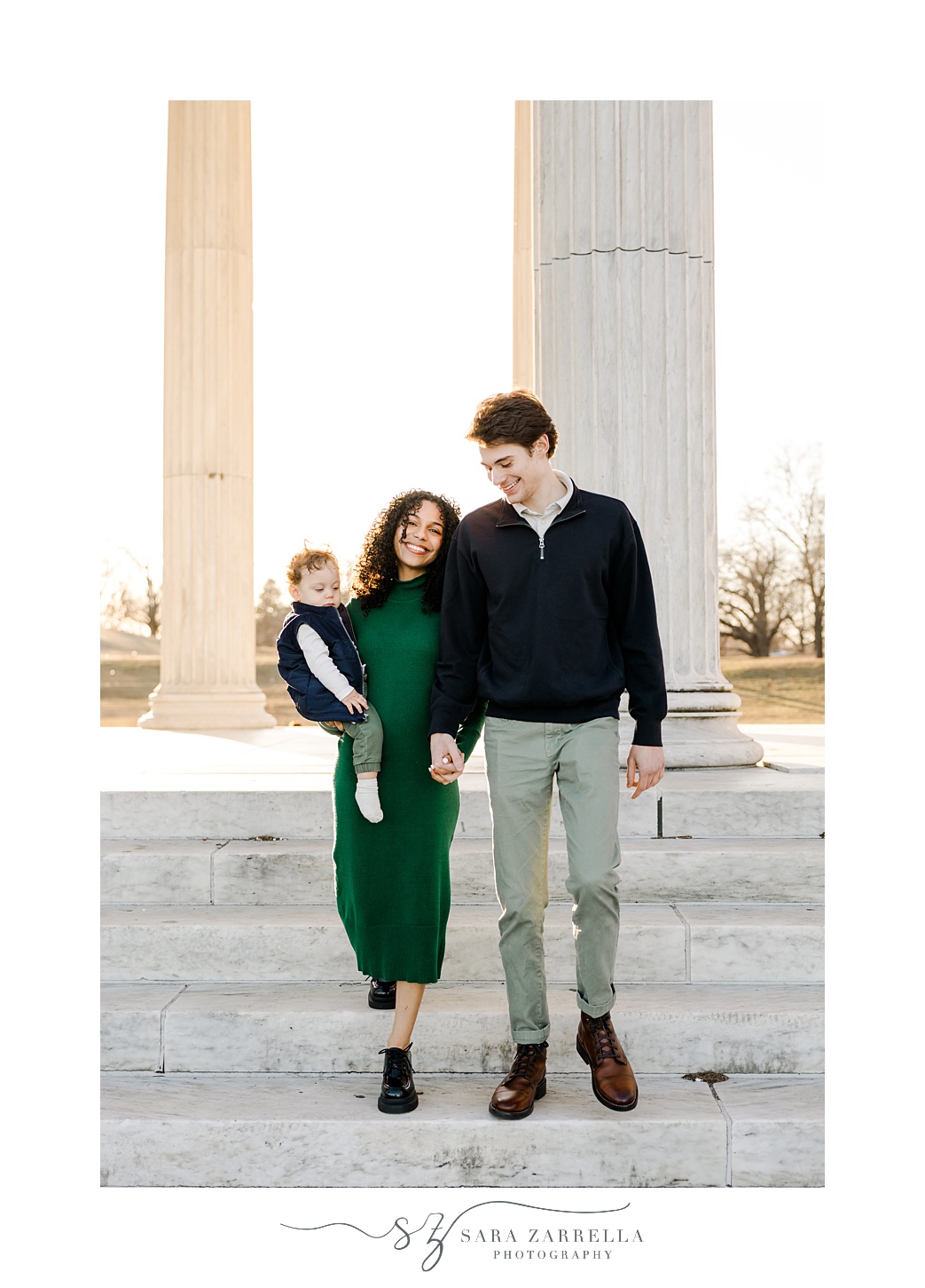 man and woman hold hands with son on their hip during family photos at Roger Williams Park