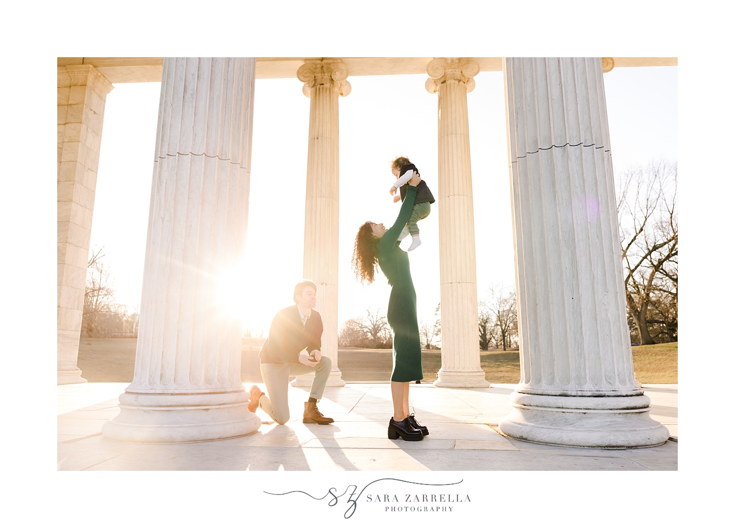 man kneels behind woman playing with their son during proposal at Roger Williams Park