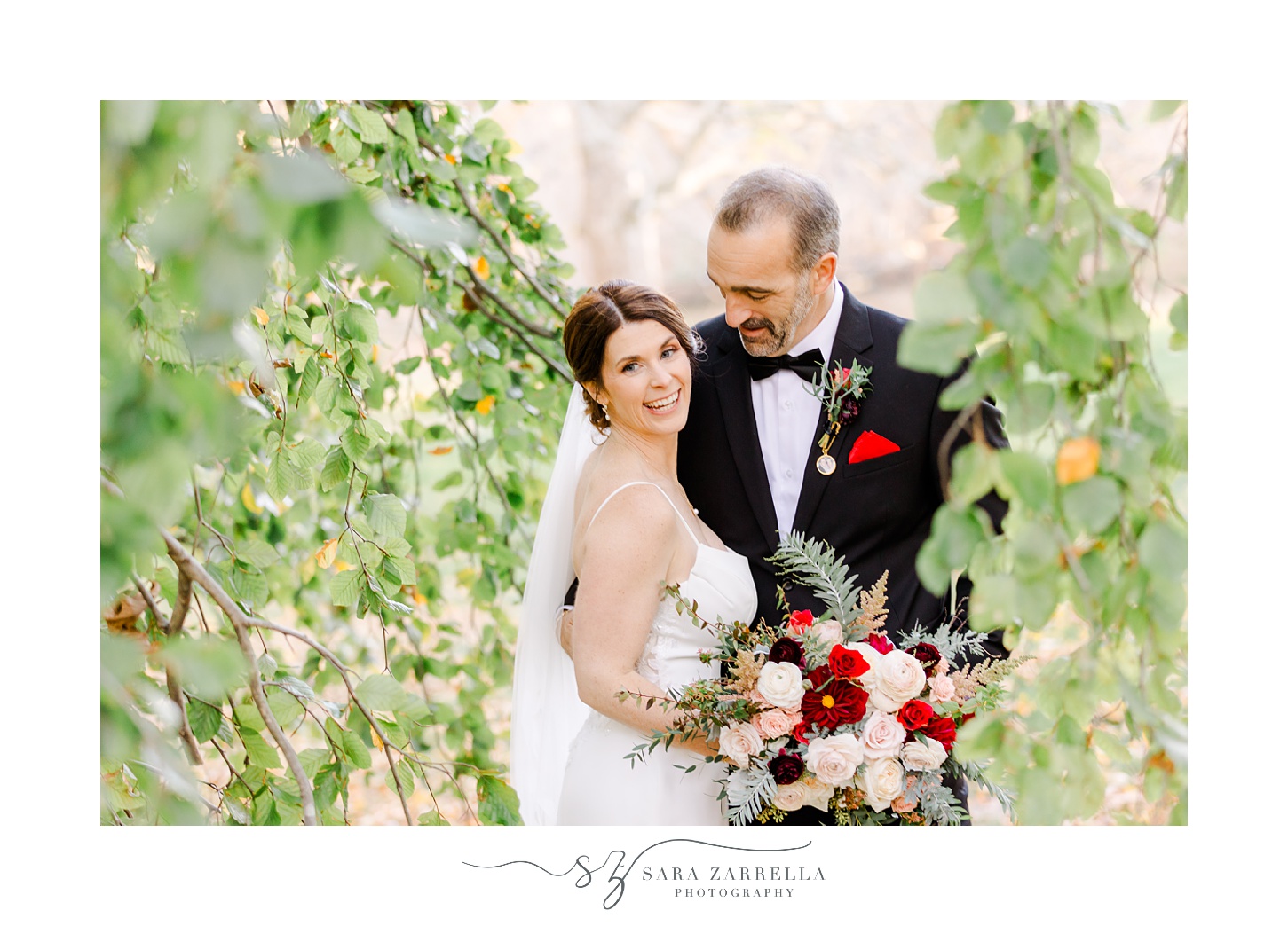 bride and groom hug between green leaves at Quidnessett Country Club
